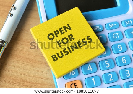 Selective focus of calculator, pen and wooden board written with text OPEN FOR BUSINESS. 