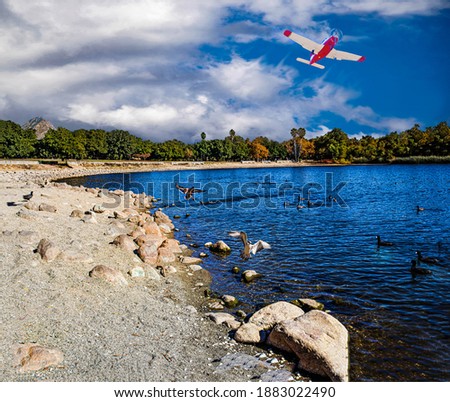 Red and white plane taking off from Brackett airport flying over the blue waters of Puddingstone lake landscape. Royalty-Free Stock Photo #1883022490