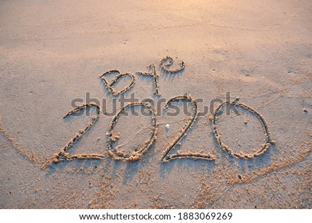 Goodbye year 2020 written on the sandy beach background.