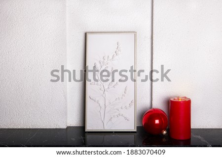 Botanical bas-relief wildflowers for wall art and red christmas ball and candle on marble shelf. 3D Flower plaster decor. Christmas decoration. Stylish and modern interior of room. . High quality