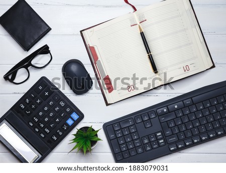 Workplace desk with keyboard, office supplies, pencil, green leaf on wood table. Office desktop. Elegant workspace with business accessories on white background with copyspace. Creative flat lay photo