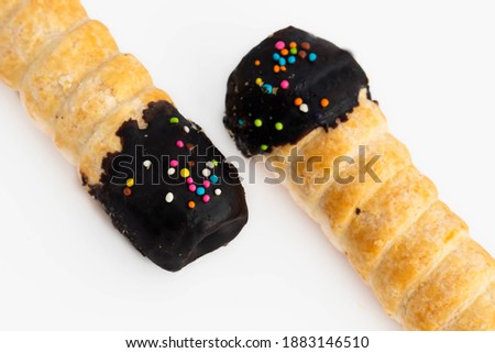 Pair Of Fresh Cannoli Cream Horns Or Swiss Rolls Having Chocolate Flavor Paste At Top And Sprinkle Of Colored Jimmies Placed Diagonally On White Background With Blank Copy Space For Custom Text