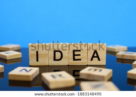 Idea word made of wooden letters on a mirror surface on a blue background