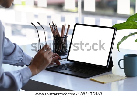Close up view of designer working on tablet computer while sitting in creative office.