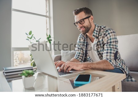 Profile side photo of young handsome man happy positive smile chat type browse laptop sit couch indoors distance work
