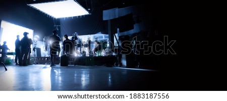 Silhouette images of video production behind the scenes or b-roll or making of TV commercial movies that film crew team lightman and videos cameraman working together with movie director in studio. Royalty-Free Stock Photo #1883187556