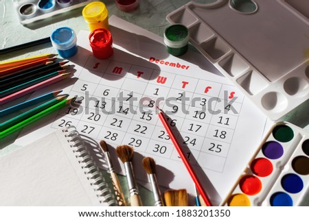Calendar for December 2021. The creative layout of the objects for drawing. December 8 is the Artist's Day. Greeting card layout Watercolor, gouache paints, colored pencils, brushes, palette, flat lay