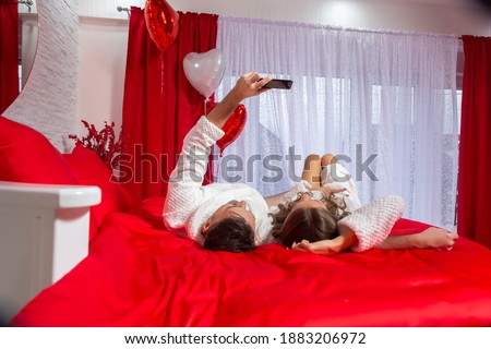 Beautiful young couple in love laying on the hotel bed, taking a selfie