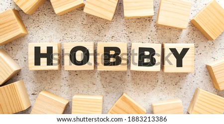 The word HOBBY consists of wooden cubes with letters, top view on a light background.