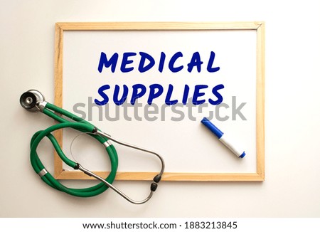 The text MEDICAL SUPPLIES is written on a white office board. Nearby is a stethoscope.