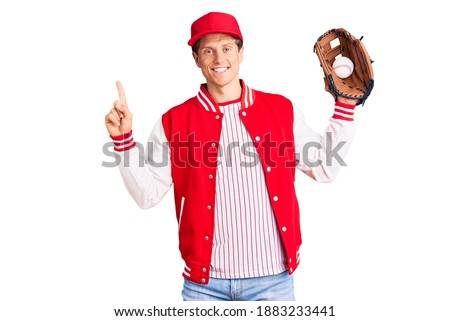 Young handsome man wearing baseball uniform holding golve and ball surprised with an idea or question pointing finger with happy face, number one 