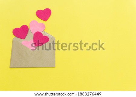 paper envelope with five pink hearts on a yellow background. valentine day concept. color of the year 2021