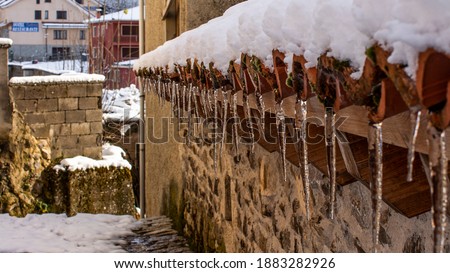 Stalactite in a snowy roof of a village