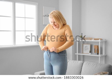 Troubled overweight woman in tight clothes at home Royalty-Free Stock Photo #1883303026