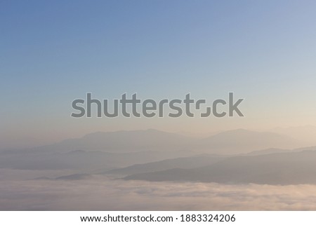 Foggy view on hill with colorful romantic blue sky in the morning with silhouette mountains. Beautiful sunlight and sea fog.