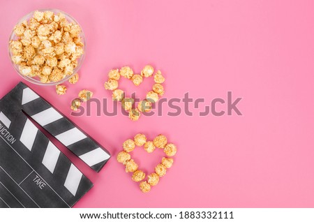 Valentine's Day movie concept. Movie clapperboard with caramel popcorn hearts with copy space