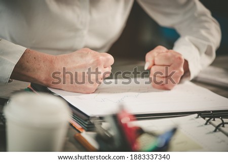 Angry businesswoman hitting her desk with her clenched fists Royalty-Free Stock Photo #1883337340