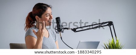 A charming woman radio host is broadcasting live on a laptop. Online radio concept. Wide screen