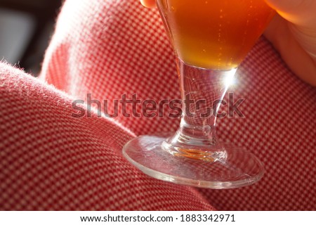 Sun flare in the reflection in a glass of beer with checkered textile background