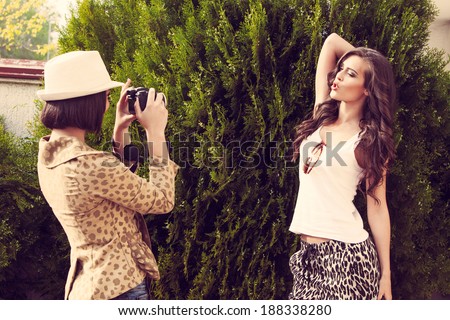 two young women take photo of each other with camera outdoor shot