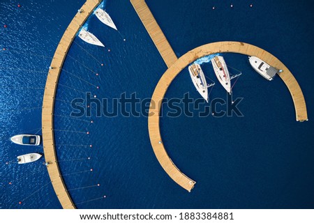 Aerial View by Drone of Yacht Club and Marina. Top view of yacht club. White boats in sea water. Marina dock yachts and small motor boats. Yacht and sailboat is moored at the quay. Parking Royalty-Free Stock Photo #1883384881