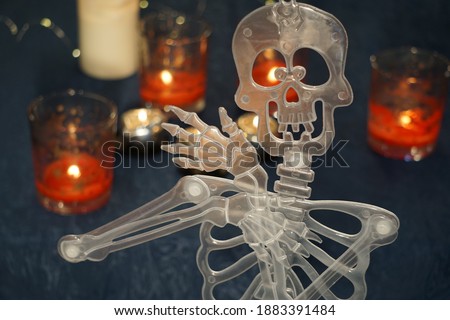 Human Skeleton Decoration And Wax Candle. Dark Blue Background And Candle Light.