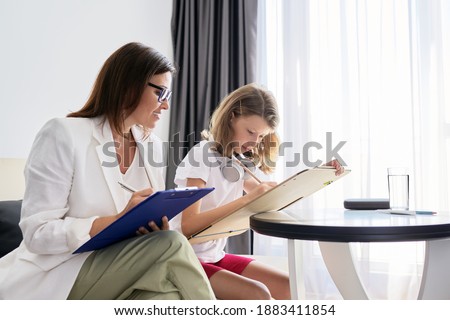 Professional family psychologist helping child, female teacher, social worker talking to a girl in office. Mental health, education training class, psychology, childhood Royalty-Free Stock Photo #1883411854
