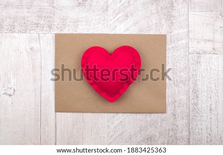 Red heart on envelope on wooden background for Valentine's day, love message, top view.
