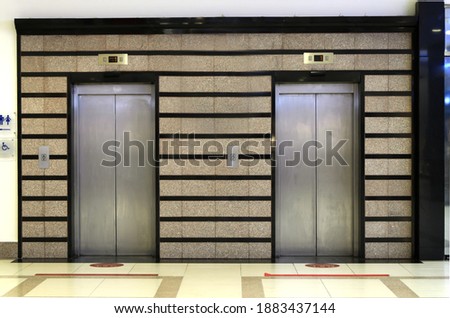 Two elevator doors. Elevator platform in business center or apartment complex. Sign-pointer lift for disabled wheelchair users. Concept: accessible environment in public places. Selective focus