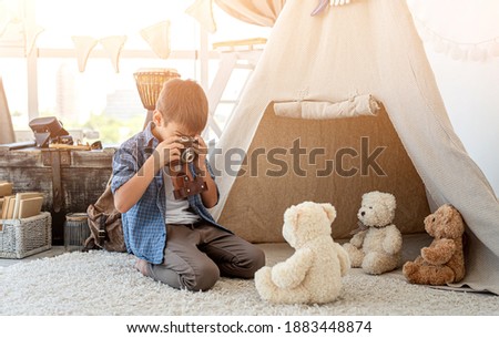 Little boy taking picture of plush teddy