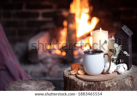 A cup with decorative elements on a wooden stump near the fireplace. The concept of a village holiday outside the city.