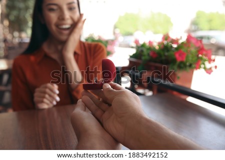 Man with engagement ring making proposal to his girlfriend in outdoor cafe, focus on hands