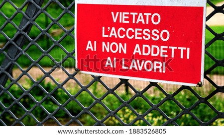 Prohibition sign in red background and white writing with written in Italian FORBIDDEN ACCESS TO NON-WORKERS on metal grating with geometric design