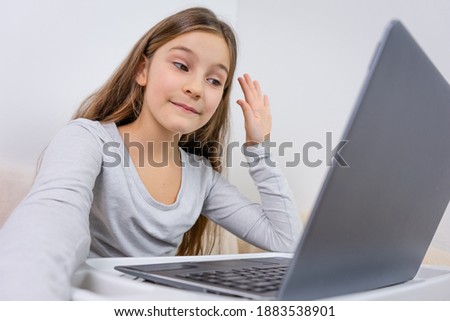 Portrait of attractive cute happy smiling girl 6-7 old sitting using laptop indoor white background distance learning