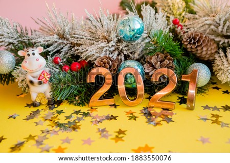 Toy bull with present on a Christmas tree branch background. Bull as a symbol of the New year. Chinese New year 2021.Winter holiday celebration. year of the ox.