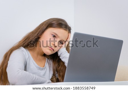 Emotional portrait of attractive nice lovely pretty cute focused cheerful girl 6 - 7 old sitting using laptop indoor white background on distance learning