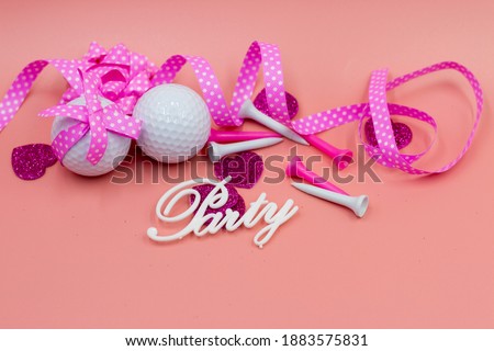 Golf ball with pink ribbon on pink background