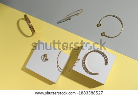 Flat lay of golden jewelry on gray and yellow background 