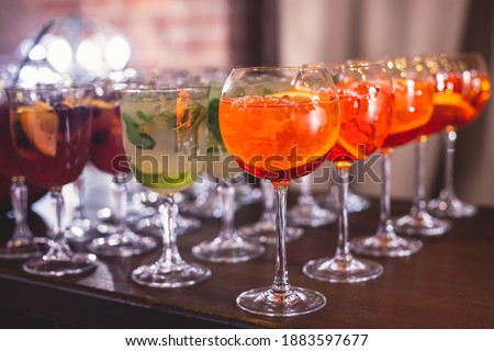 View of alcohol setting on catering banquet table, row line of different colored alcohol cocktails on a party, martini, vodka, spritz and others on decorated catering bouquet table event
