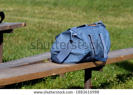 A blue duffel bag on a bench.  Royalty-Free Stock Photo #1883616988