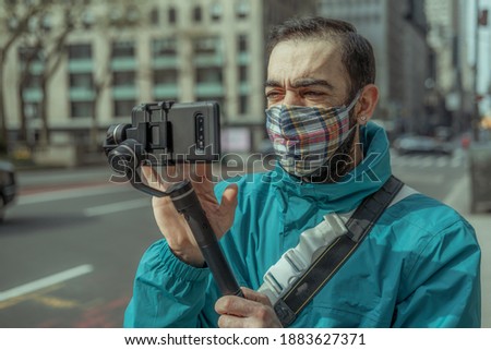 Man using phone with stabilizer and taking pictures and live video in New York city. Vlog, video blogging, street photography concept.