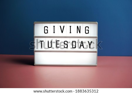 Giving Tuesday word in light box on blue and pink background
