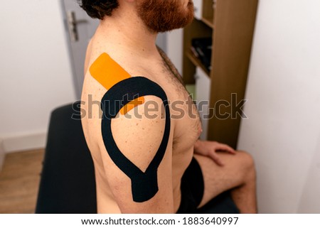 Stock photo of bearded man sitting on stretcher and looking at front during treatment in rehabilitation.