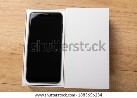 Picture of new smartphone unboxing in front of wooden background