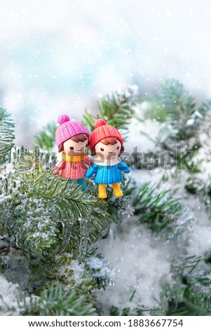 cute toy girls on snowy frosty fir tree. beautiful winter scene. festive winter season. Christmas and New Year holiday background