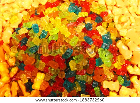 Colorful texture using as background. A lot of sweets. Background 3d rendering illustration. Orange and black multiple jelly candies in powdered sugar. Confectionery wallpaper concept. Copy space
