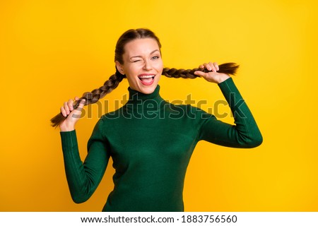 Portrait of attractive cheerful girl winking making tails having fun isolated on bright yellow color background
