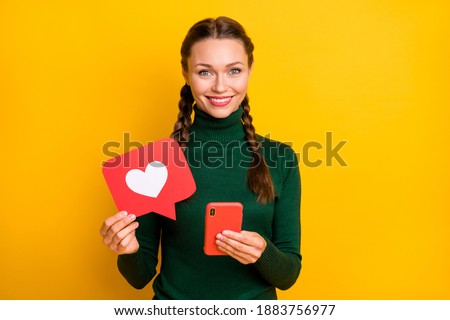 Photo portrait happy woman with braids showing heart icon keeping mobile phone isolated vivid yellow color background