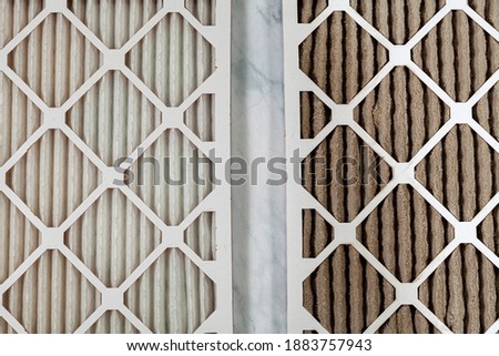 Side by side close up view of a new unused and an old heavily clogged dirty air filters. Image emphasizes the role of framed filters in improving air quality and preventing respiratory problems. Royalty-Free Stock Photo #1883757943