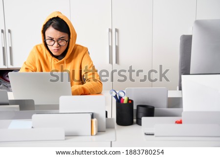 Young unhappy stressed handsome designer woman working in office. Angry woman wearing glasses with too much work in office
